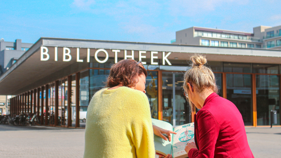 Twee dames lezen folder op het Boekenplein voor de bib