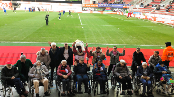 vrijwilligers en bewoners van Ruiterslaan poseren in groep in het Regenboogstadion 