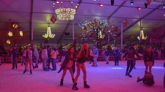 veel schaatsers op de ijspiste met sfeerverlichting
