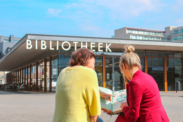 Twee dames lezen folder op het Boekenplein voor de bib